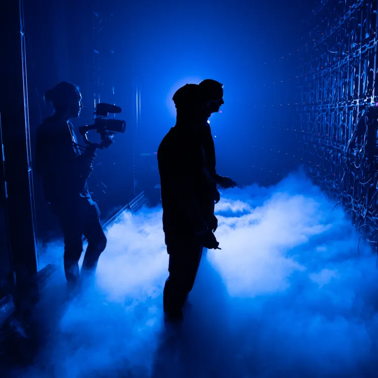 A speaker walks onto a blue-lit stage at a Wealth Outside Wall Street event.