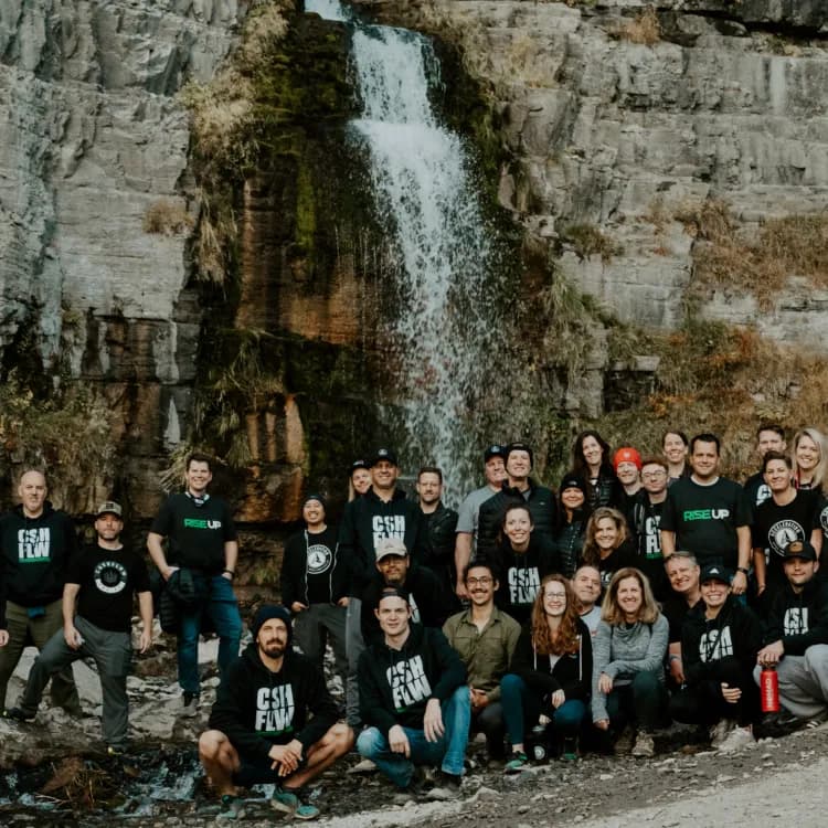 Wealth Outside Wall Street community members gather in front of a waterfall.